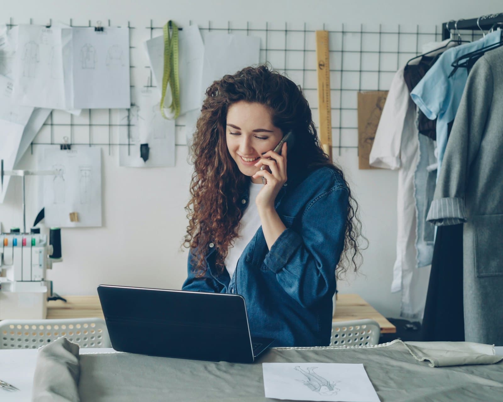 Founder laughing on the phone while working on her laptop in her studio